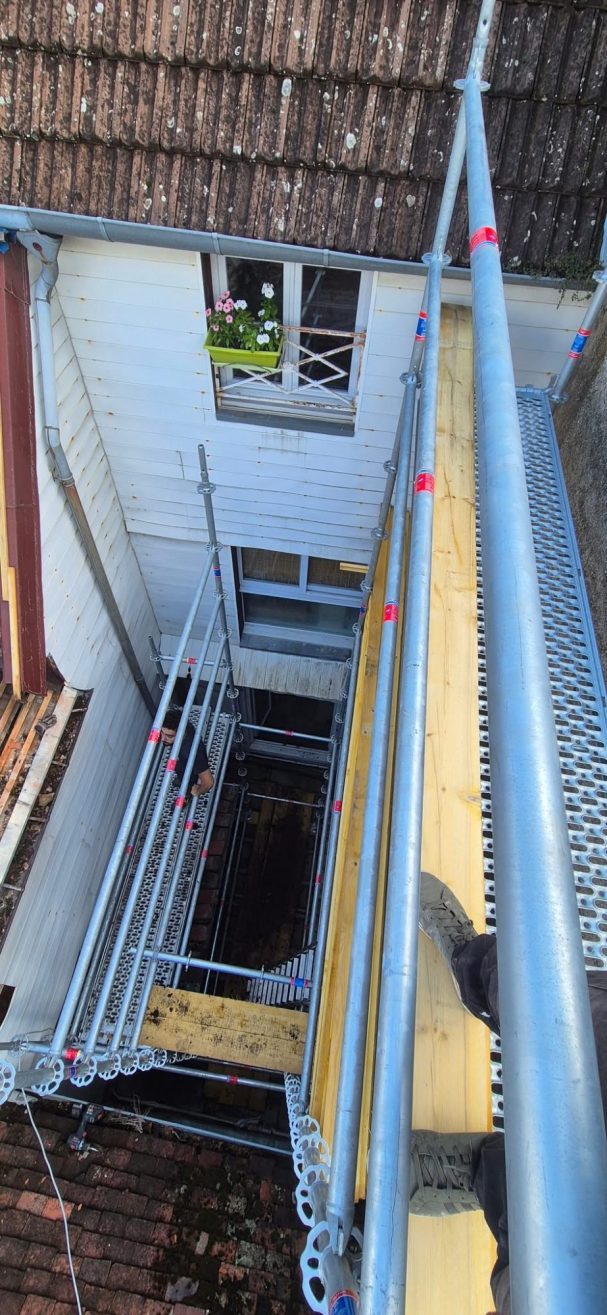 Accès complexe Langres Échafaudage bleu installé sur un bâtiment, avec vue sur une cour intérieure.