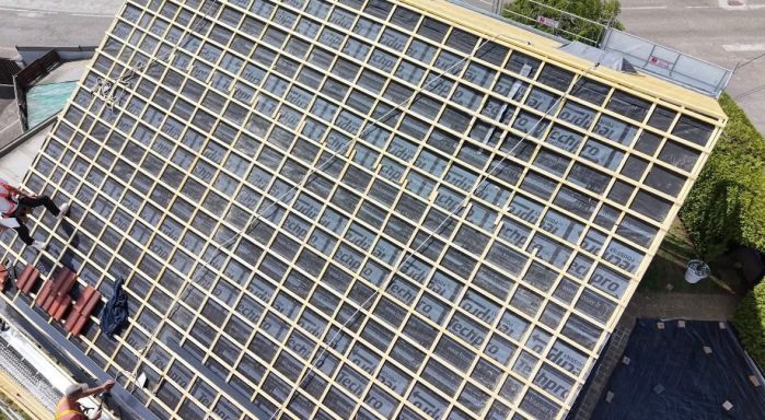 Toit recouvert de panneaux solaires, avec des ouvriers en travaux.