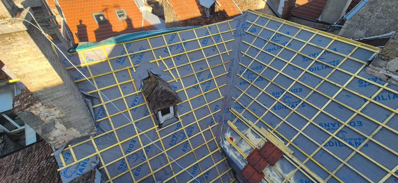 Lattage à Langres Toit en rénovation avec une couverture bleu et des lignes jaunes de support.