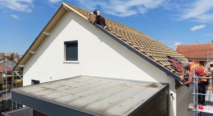 Homme sur le toit en train de travailler sur la couverture d'une maison.