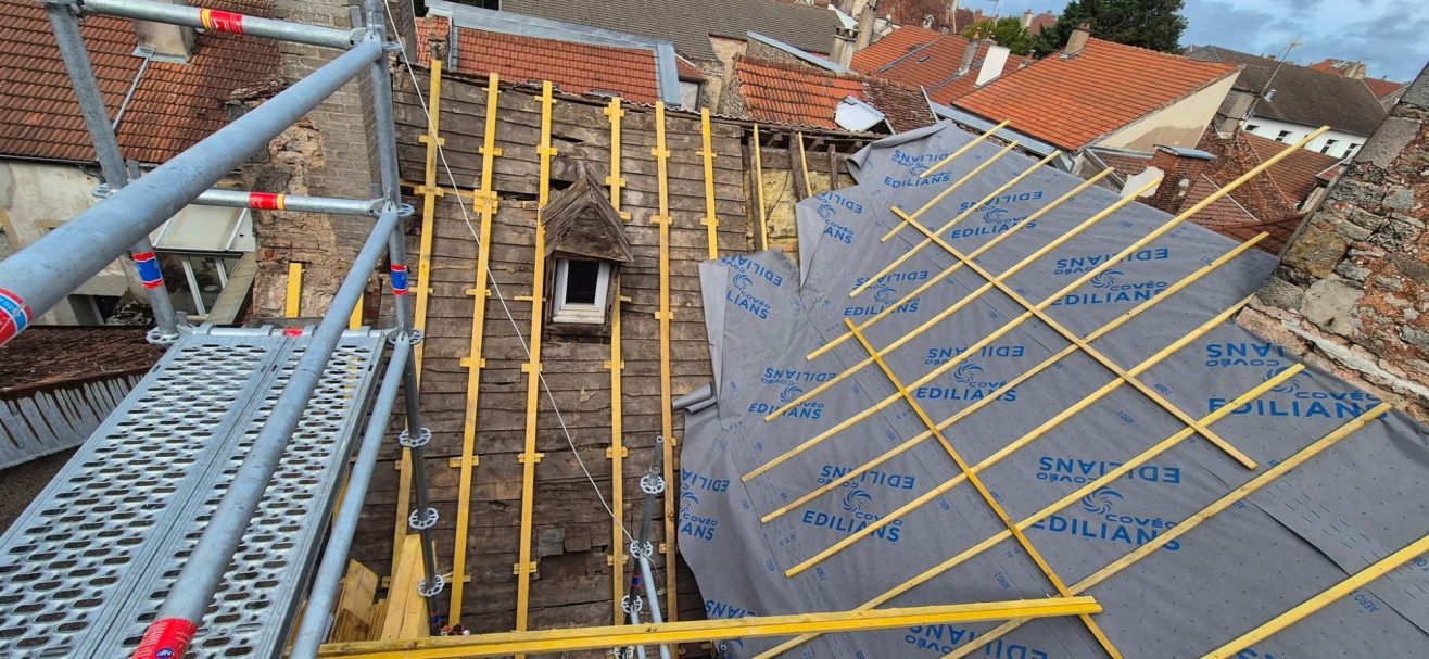 Pose de sous-toiture et contre-lattage à Langres Travaux de toiture avec des échafaudages et des matériaux de couverture en place.