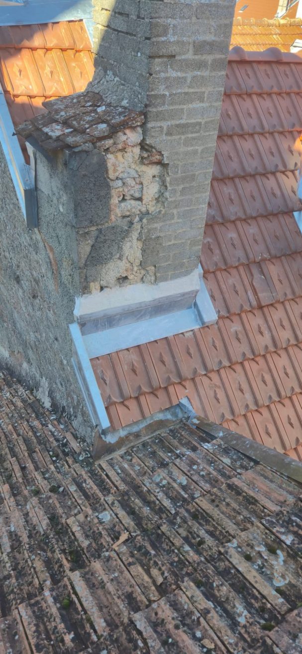 Garniture de cheminée à Langres Vue en plongée d'un toit en tuiles avec un chemin de cheminée en pierre.