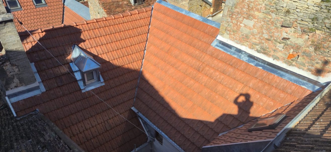 Lucarne en zinc à Langres Toit en tuiles rouges avec une ombre projetée, vue d'en haut.